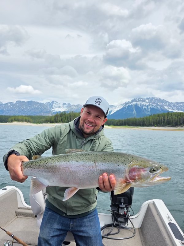 Man holding rainbow trout on fishing trip with Canmore fishing Adventures