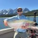 Man holding rainbow trout on fishing trip with Canmore fishing Adventures