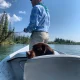 Man fishing in Canmore on a small boat, with a dog